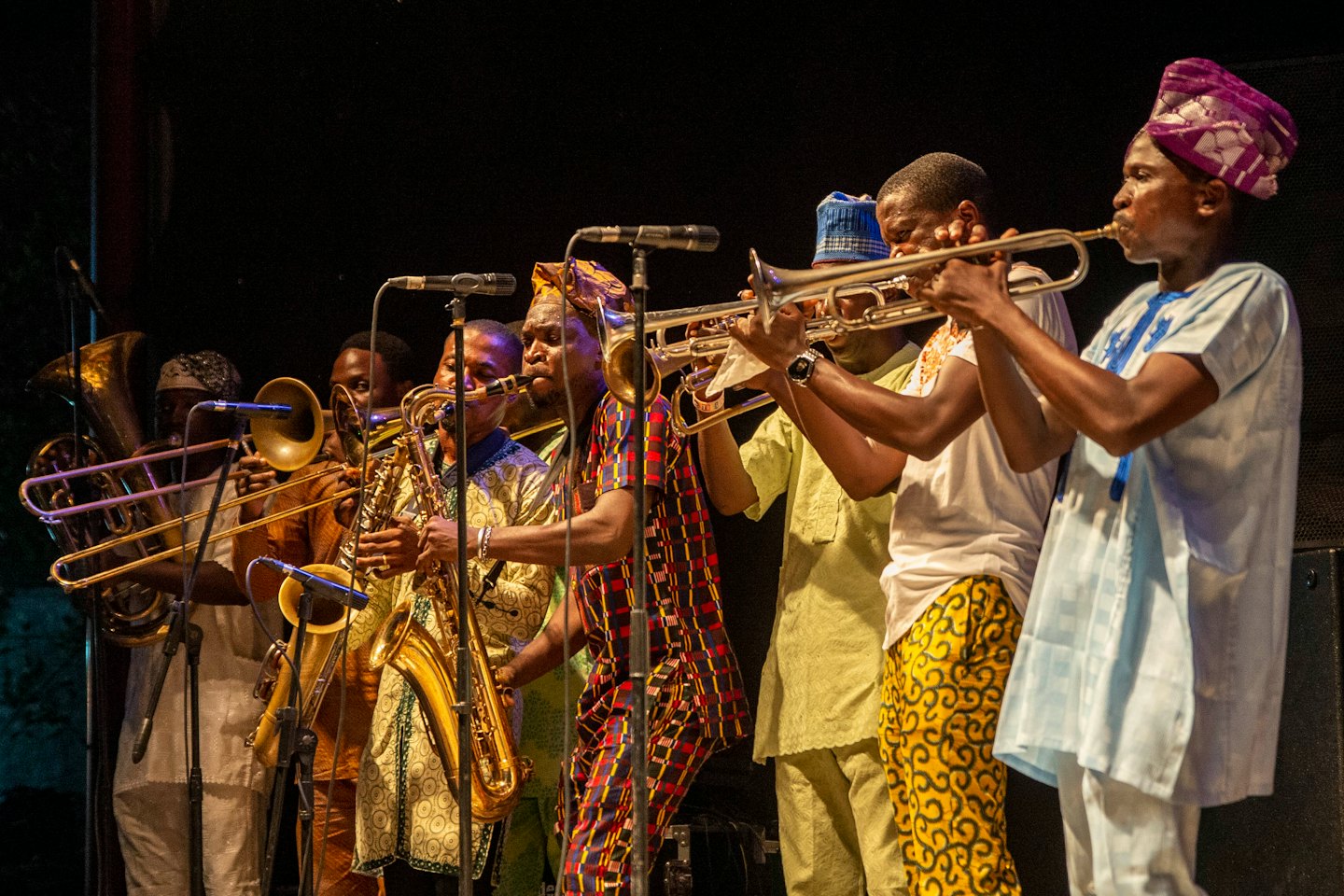Musicians playing brass instruments and saxophones on stage.