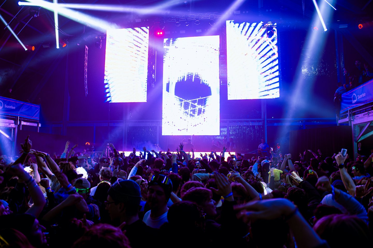 Crowd with hands raised at an indoor music event.
