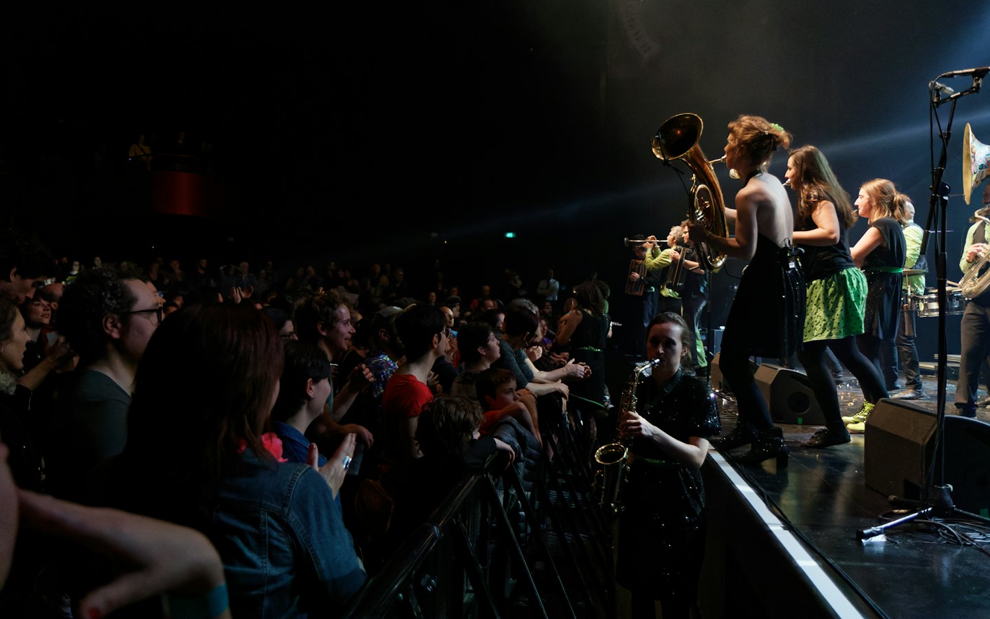 A brass band performs on stage for an energetic crowd.