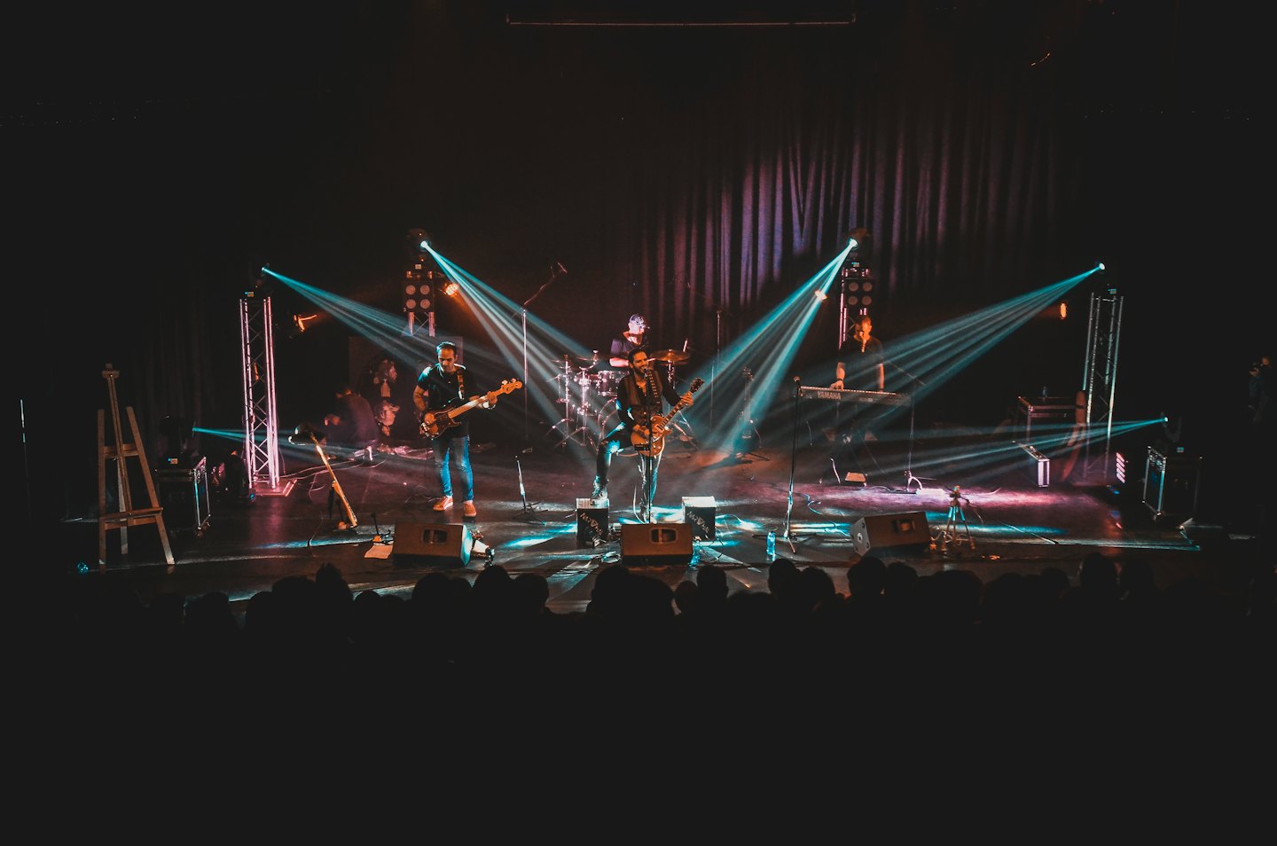 Band plays energetically on a stage with colorful spotlights.