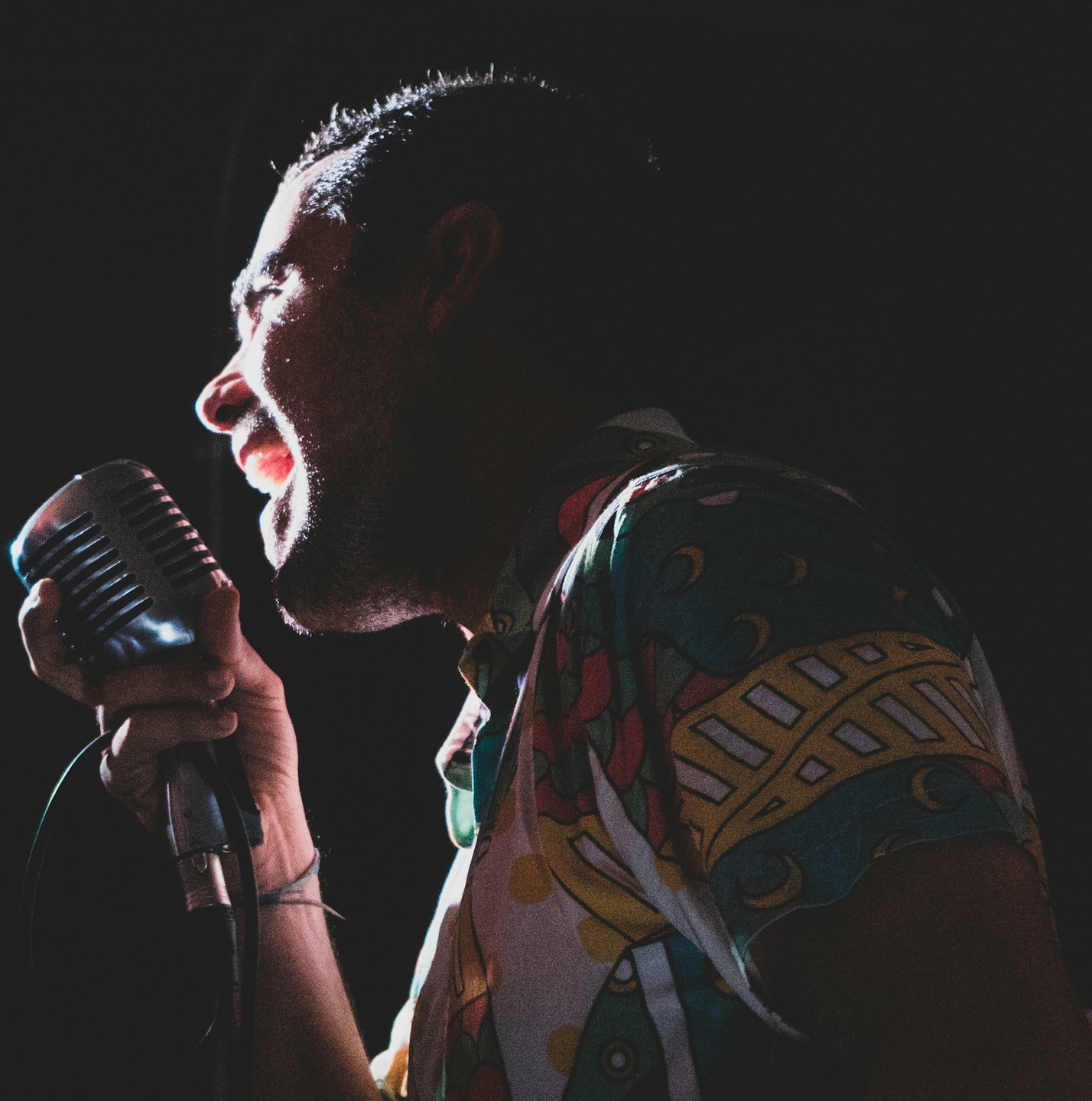 Performer singing passionately into a vintage silver microphone.
