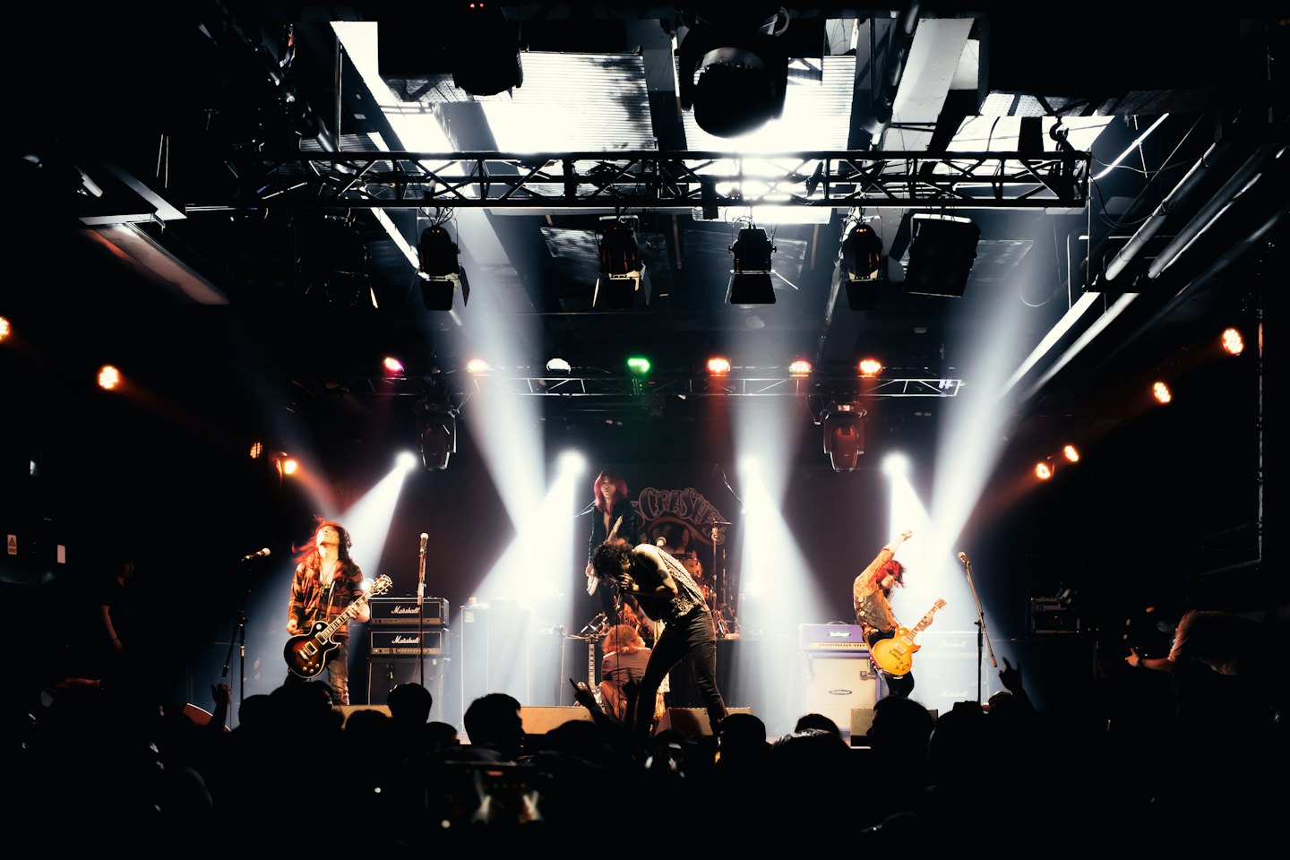 Rock band plays energetically on a brightly lit concert stage.